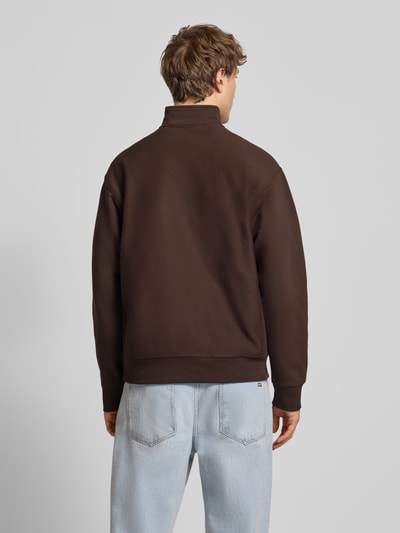 Männermodel trägt Sweatshirt mit Label-Stitching von Carhartt Work In Progress aus Baumwoll-Mix, lockerer Schnitt, Stehkragen, Rückenlänge 70 cm, Ärmellänge 64 cm, gerippte Abschlüsse, Ganzkörperansicht Rückansicht.