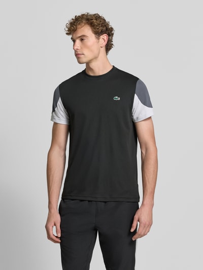 Männermodel trägt Regular Fit Sport-T-Shirt im Colorblock-Design von Lacoste, Herren Sport-T-Shirt, Schwarz, Grau, Ganzkörperansicht von vorne.
