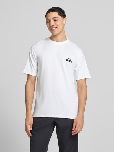 Männermodel trägt weißes T-Shirt mit Rundhalsausschnitt und Logo von Quiksilver, Material-Mix mit Stretch-Anteil, Regular-Fit, Rückenlänge 75 cm, Ganzkörperansicht von vorne.
