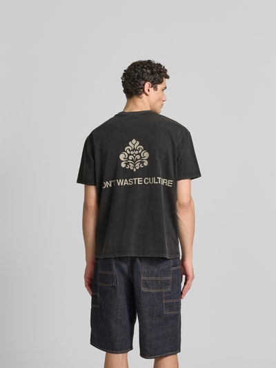 Männermodel trägt Relaxed Fit T-Shirt aus Baumwoll-Mix von Don´t Waste Culture im Used-Look mit Label-Details, Ganzkörperansicht Rückansicht. Rückenlänge bei Größe M: 68 cm.