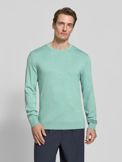 Männermodel trägt Strickpullover mit geripptem Rundhalsausschnitt von MCNEAL in Mint, feine Struktur, glatte Oberfläche, Ganzkörperansicht von vorne. Taillierte Passform, leicht überschnittene Schultern, gerippte Abschlüsse, Rückenlänge und Ärmellänge wie bei Größe M.
