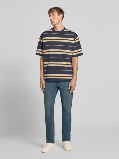 Männermodel trägt Straight Fit Jeans mit Lyocell-Anteil Modell 'GLENN' von JACK & JONES im Used-Look, 5-Pocket-Design, Ganzkörperansicht von vorne.