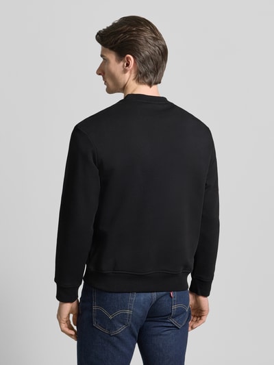 Męski model nosi Sweatshirt mit Logo-Print und Rundhalsausschnitt od ARMANI EXCHANGE, czysta bawełna, krój loose fit, czarny kolor, widoczny ściągacz, długość tyłu w rozmiarze M: 65 cm, długość rękawa w rozmiarze M: 61 cm, widok całej sylwetki od tyłu.