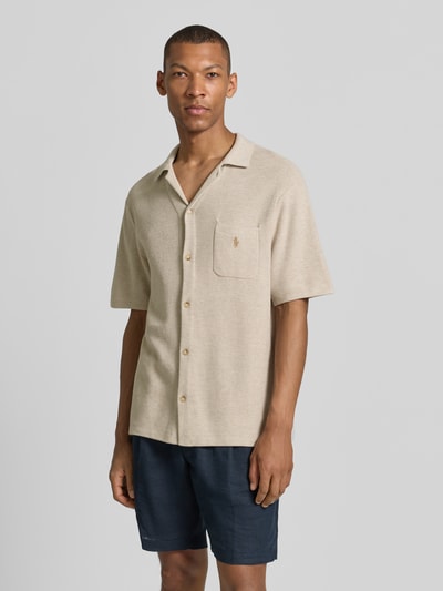 Männermodel trägt Regular Fit Poloshirt aus reiner Baumwolle von Polo Ralph Lauren in Beige, glatte Textur, Ganzkörperansicht von vorne.
