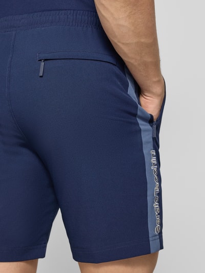 Männermodel trägt Shorts mit Logo-Print Modell 'GOCCIA' von SERGIO TACCHINI in Dunkelblau, Material-Mix, Detailaufnahme Rückansicht.