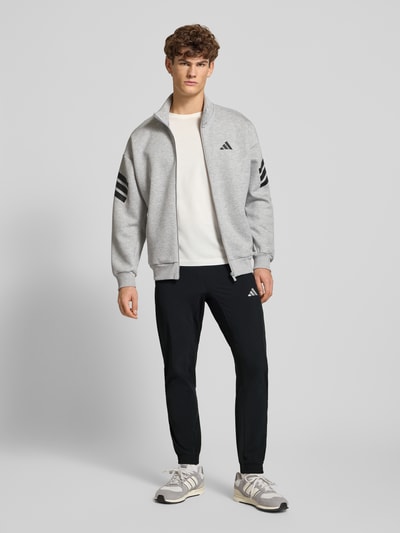 Männermodel trägt Sweatpants mit elastischem Bund von adidas Training in Schwarz, Material-Mix mit Stretch-Anteil, Lockerer-Schnitt, Französische-Eingrifftaschen, Label-Print, Ganzkörperansicht von vorne.