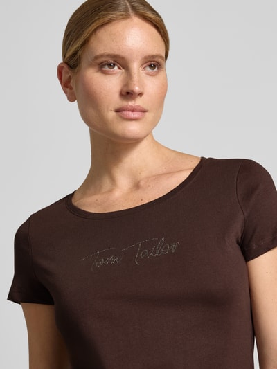 Kobieta nosi Regular Fit T-Shirt aus reiner Baumwolle od Tom Tailor, Damski t-shirt, brązowy kolor, gładka faktura, Nahaufnahme górnej części ciała.