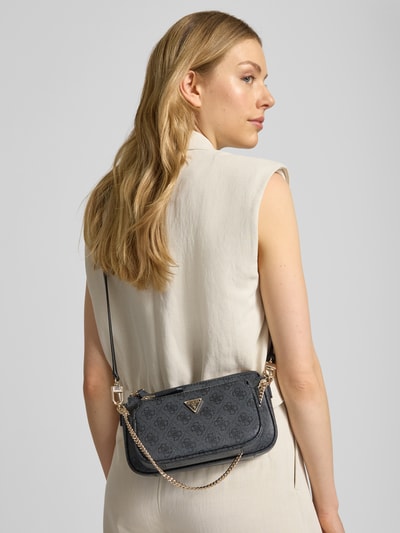Kobiece modelka nosi Pouch mit Label-Applikation Modell 'NOELLE II' od Guess, kolor ciemnoszary, aplikacja z metką, uchwyt, pasek na ramię, główna przegroda z zamkiem błyskawicznym, szerokość w rozmiarze 1: 24 cm, długość w rozmiarze 1: 13 cm, głębokość w rozmiarze 1: 5 cm, długość paska na ramię w rozmiarze 1: 122 cm, faktura skóropodobna, Ganzkörperansicht Rückansicht.