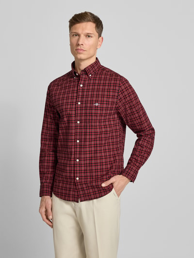 Männermodel draagt Gant Vrijetijdsoverhemd van puur katoen, regular fit, button-downkraag, knoopsluiting, borstzak, labelstitching, bordeauxrood met rood-zwart ruitpatroon, lichtbeige broek, vooraanzicht bovenlichaam. Ruglengte maat M: 76 cm, schouderbreedte: 56 cm, mouwlengte: 65 cm.