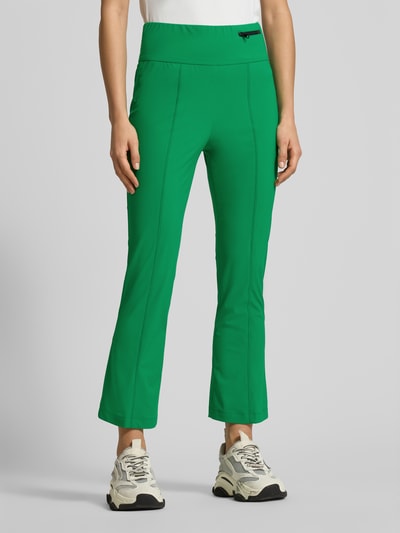 Frauenmodel trägt Loose Fit Jogpants mit breitem Bund von Marc Cain in kräftigem Grün, Teilungsnähte, Reißverschlusstasche, Elastischer-Material-Mix, Ganzkörperansicht von vorne.