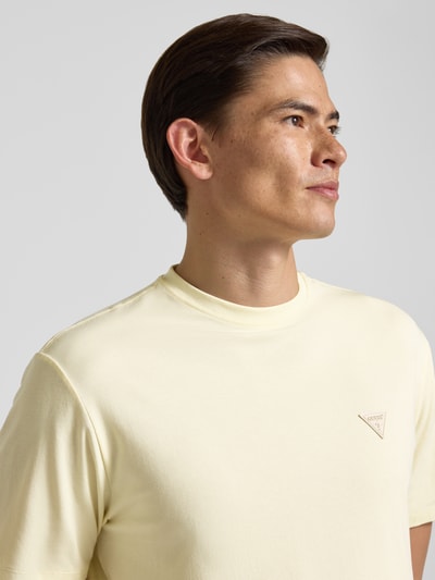Männermodel trägt T-Shirt mit Logo und Rundhalsausschnitt von Guess aus Baumwoll-Mix mit Modal-Anteil, Relaxed-Fit, Nahaufnahme Oberkörper.