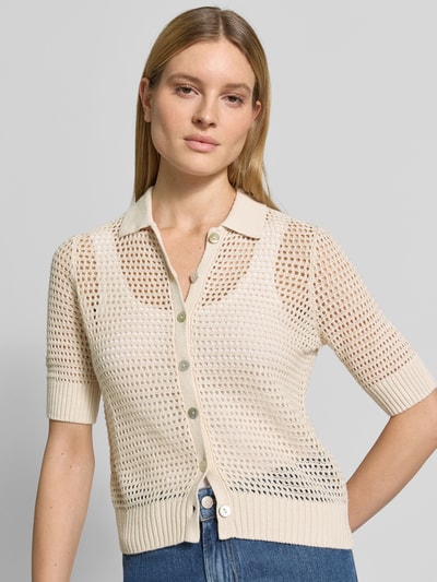 Modelka nosi Strickjacke aus Leinen mit 1/2-Arm od Christian Berg Woman, beżowa, krój slim fit, półprzezroczysty len, krótki rękaw, polo, widok na górną część ciała z przodu