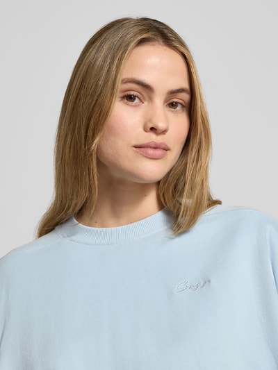 Vrouwenmodel draagt Cropped sweatshirt uit katoenmix Model 'C_EFEM_1' van BOSS Orange, look: effen, applicatie met labelstitching, loose fit, ronde hals, lange mouw, sweatmateriaal, detailopname bovenlichaam.