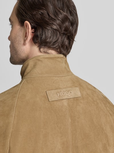 Mężczyzna nosi Regular Fit Lederjacke aus echtem Ziegenleder Modell 'LORIDGE' od HUGO w jednolitym beżowym kolorze i zamszowej fakturze, detal z logo z tyłu, ujęcie z tyłu zbliżenie na ramiona.