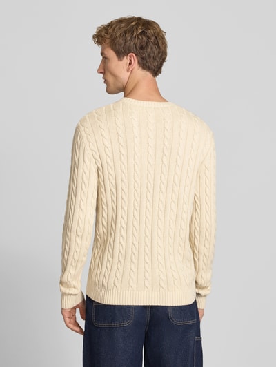 Männermodel trägt Slim Fit Strickpullover reine Baumwolle von REVIEW in Creme mit Zopfmuster, gerippten Bündchen, Rückansicht, Ganzkörperansicht.