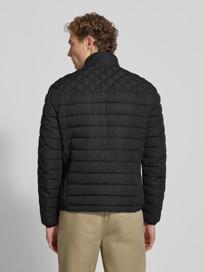 Männermodel trägt schwarze Steppjacke mit Stehkragen und Reißverschlusstaschen von Christian Berg Men, Regular Fit, Ganzkörperansicht Rückansicht.