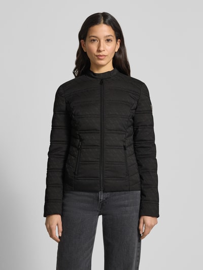 Kobiece model prezentuje czarną kurtkę pikowaną z wzorem z logo, mieszanka materiałów z dodatkiem streczu, krój slim fit, stójka, zamek błyskawiczny, kieszenie zapinane na zamek, NEW VONA od Guess, widok na całe ciało z przodu.