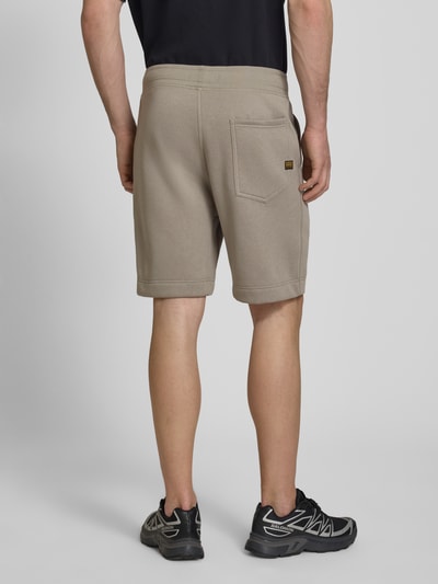 Männermodel trägt Sweatshorts mit elastischem Bund von G-Star Raw aus Baumwoll-Mix in Regular-Fit, Farbe Beige, Ganzkörperansicht Rückansicht.