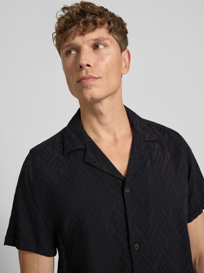 Männermodel trägt Regular Fit Freizeithemd aus Viskose-Baumwoll-Mix Modell 'Bijan' von DRYKORN, Allover-Look, schwarz, Nahaufnahme Oberkörper. Rückenlänge Größe M: 78 cm, Schulterbreite: 45 cm, Ärmellänge: 24 cm.