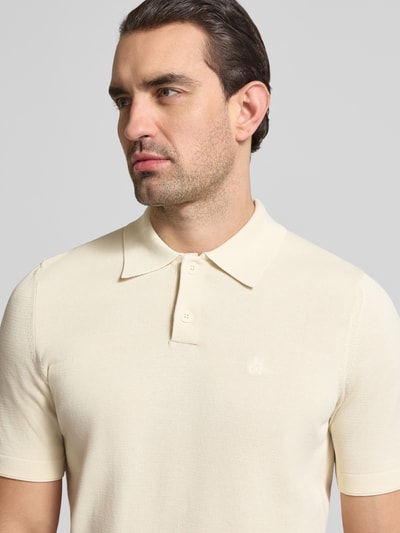 Mężczyzna nosi Regular Fit Poloshirt aus reiner Baumwolle od Marc O'Polo, efekt: jednolity kolor, wykończenie: dzianina, wyhaftowane logo, kołnierzyk polo, krótki rękaw, zrolowany brzeg, materiał: bawełna, zbliżenie na górną część ciała