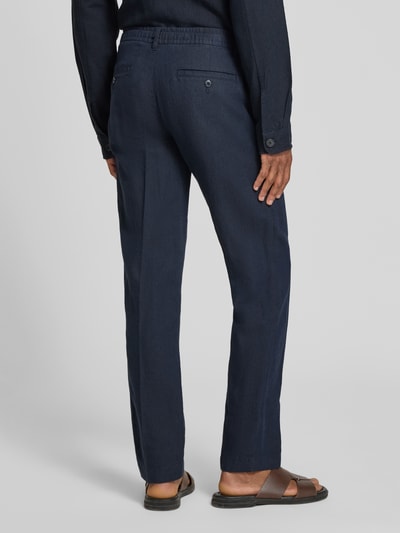 Männermodel trägt Straight Leg Leinenhose mit Tunnelzug Modell 'LEROY' von SELECTED HOMME in Dunkelblau, Flammgarnstruktur, Ganzkörperansicht Rückansicht.