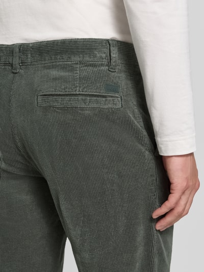 Männermodel trägt Tapered Fit Chino aus Baumwoll-Mix von BOSS Orange in grünlicher Farbe, feine Cordstruktur, Nahaufnahme Rückansicht.