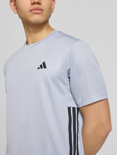 Männermodel trägt Regular Fit Sport T-Shirt mit Logo-Print von adidas Training, unifarben, Rundhals, Kontraststreifen, Nahaufnahme Oberkörper.