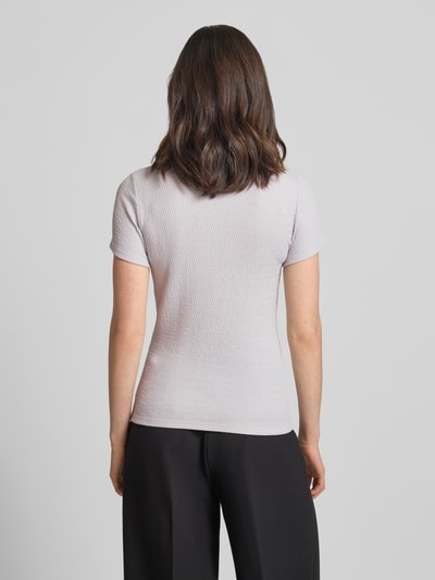 Vrouwenmodel draagt T-Shirt met Label-Detail van Marc Cain in lichte kleur, elastische materiaal-mix, aansluitende fit, ruglengte 55 cm, volledige lichaamsweergave achterkant.