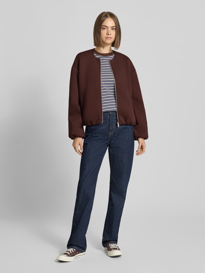 Modelka nosi Regular Fit Sweatjack mit Viskose-Anteil model 'LELLIE' od ONLY, damska bluza rozpinana, ciemny brąz, dżinsy, widok całej sylwetki z przodu.