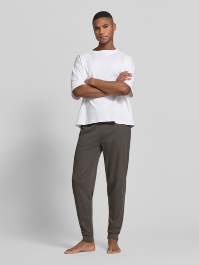 Męski model nosi Lounge-Hose mit elastischem Bund und Eingrifftaschen von Christian Berg Men, bawełna, krój regular fit, wpuszczane kieszenie, kolor ciemnobrązowy, długość wewnętrzna nogawki w rozmiarze M: 40 cm, całopostaciowy widok z przodu.