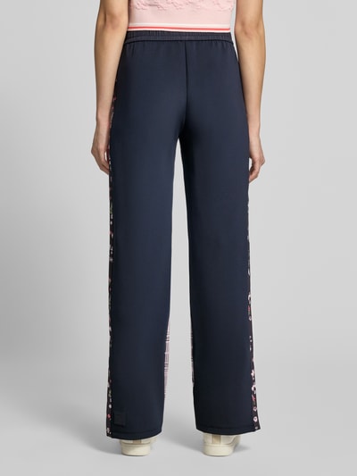 Kobiece modelka nosi Straight Fit Hose mit elastischem Bund od Marc Cain, ciemnoniebieskie, kwiatowe detale, elastyczny pas, tunel, Szerokość w rozmiarze 36: 38 cm, Długość wewnętrzna nogawki w rozmiarze 36: 68 cm, widok całej sylwetki z tyłu.