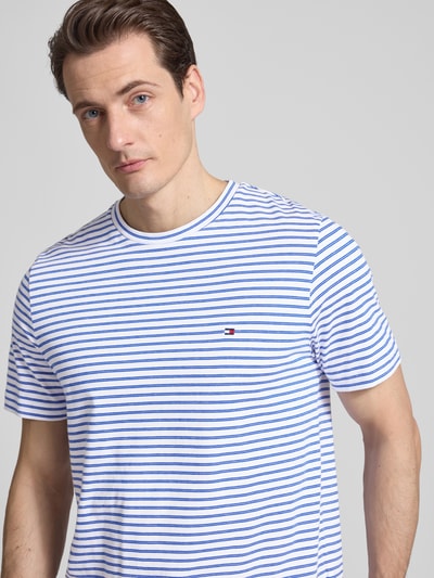Männermodel trägt Regular Fit T-Shirt aus reiner Baumwolle von Tommy Hilfiger, Optik:Allover-Muster, gestreift, Logo-Stitching, Rundhals, Kurzarm, Nahaufnahme Oberkörper.