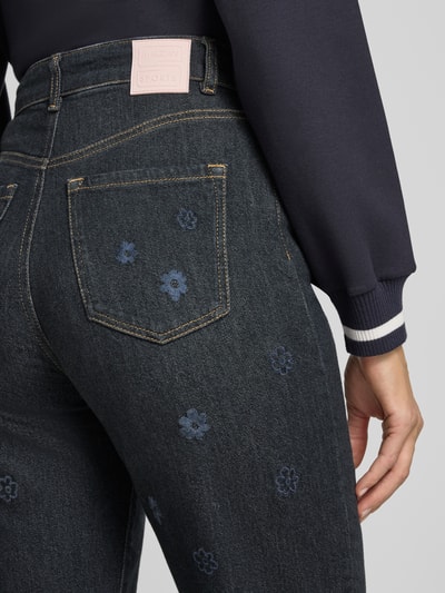 Frauenmodel trägt Straight Fit Jeans aus reiner Baumwolle von Marc Cain mit floralem Allover-Stitching und 5-Pocket-Design, Nahaufnahme Rückansicht.