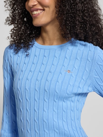 Vrouwenmodel draagt gebreide pullover met kabelpatroon en labelstitching van Gant, katoenmix met stretch, slim fit, ronde hals, nahaufnahme bovenlichaam.