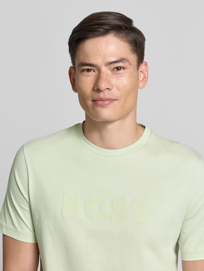 Männermodel trägt Regular Fit T-shirt uit puur katoen model 'TE_LOGO' van BOSS Orange in look: effen met logoprint, ronde hals en korte mouw, nahaufnahme oberkörper.