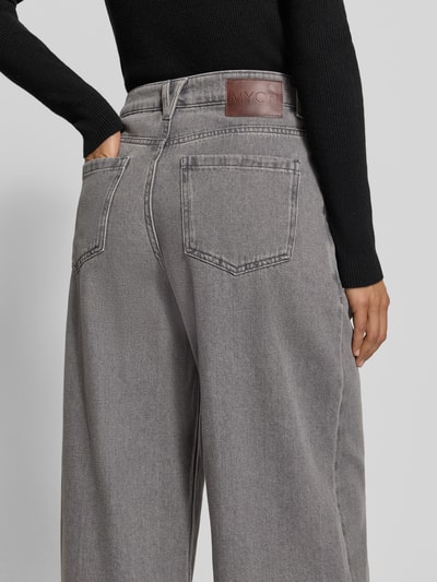 Frauenmodel trägt Wide Fit Jeans mit gelegten Falten von MYON aus reiner Baumwolle in Grau, sichtbare Gesäßtaschen, Ganzkörperansicht Rückansicht.