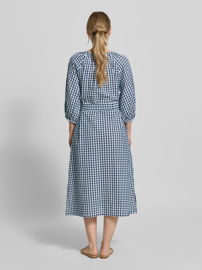 Modelka kobieca ma na sobie Regular Fit Freizeitkleid aus reiner Baumwolle od s.Oliver RED LABEL w niebiesko-biały wzór, długość midi, okrągły dekolt, pasek wiązany, rękaw 3/4, prosty dół, tkanina crinkle, widoczna struktura bawełny, widok całej sylwetki z tyłu.