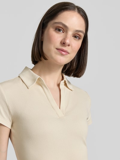 Frauenmodel trägt T-Shirt mit Polokragen Modell 'Kleoh Polo' von Someday in creme mit Ripp-Optik und V-Ausschnitt, Nahaufnahme Oberkörper. Baumwoll-Elasthan-Mix, Slim Fit, Rückenlänge bei Größe 36: 60 cm.