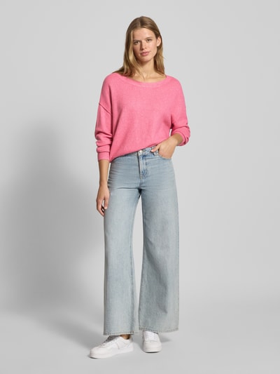 Frauenmodel trägt Strickpullover mit tiefem U-Boot-Ausschnitt von Review, Oversized, Material-Mix mit Stretch-Anteil, gerippte Abschlüsse, rosa, kombi mit Jeans und Sneakern, Ganzkörperansicht von vorne.