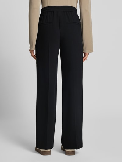 Frauenmodel trägt Hose mit elastischem Bund und Galonstreifen von Marc Cain in Schwarz, mit Bügelfalten, Regular Fit, Ganzkörperansicht Rückansicht.