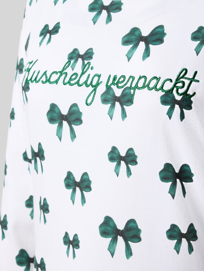 Frauenmodel trägt Relaxed Fit Nachthemd aus reiner Baumwolle von LOUIS & LOUISA, weiß mit grünen Schleifen und Stickerei, Nahaufnahme Oberkörper.