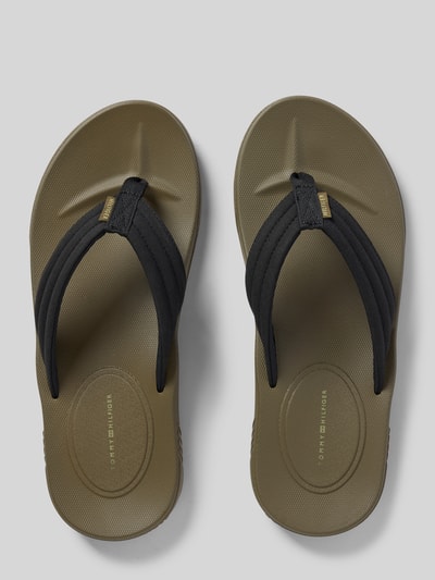 Produktfoto, Flip Flops mit Label-Applikation von Tommy Hilfiger, unifarben in Olivgrün mit schwarzem Riemen, flache Sohle, Schlupfschuh, strukturierte Oberfläche.