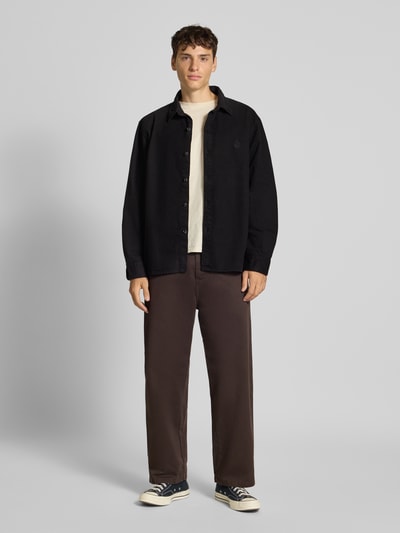 Männermodel trägt Regular Fit Freizeithemd mit Kentkragen Modell 'SEBASTIAN' von Edwin, schwarze Baumwolle, Logo-Stitching, Ganzkörperansicht von vorne.
