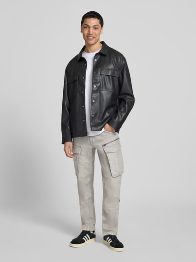 Męski model nosi Regular Tapered Fit Hose mit Cargotaschen Modell 'Rovic' von G-Star Raw, bawełna z elastanem, kolor szary, efekt used, krój tapered fit, kieszenie cargo, szerokość w rozmiarze 32/32: 44 cm, długość nogawki od wewnątrz: 78 cm, całopostaciowy widok z przodu.