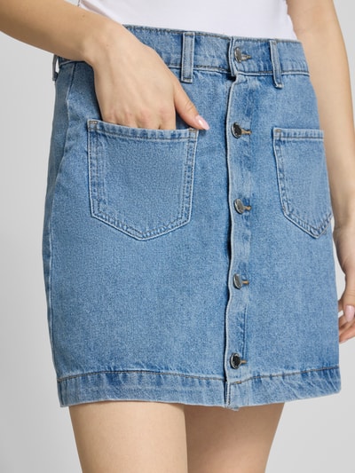 Frauenmodel trägt Schmaler Jeansrock aus reiner Baumwolle Modell 'AMAZING' von Only in hellblauem Denim mit Kontrastnähten, Nahaufnahme Oberkörper.