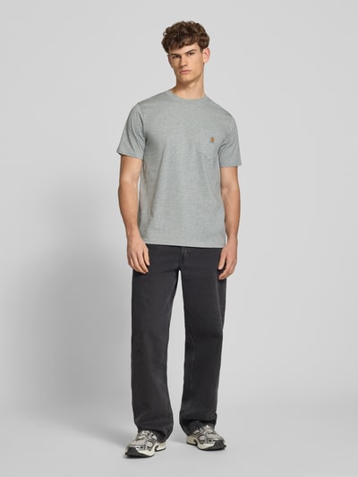 Männermodel trägt Regular Fit T-Shirt mit Logo-Patch von Carhartt Work In Progress in Grau aus Reine Baumwolle mit Brusttasche, Rundhalsausschnitt, Rückenlänge bei Größe M 70 cm, Ganzkörperansicht von vorne.