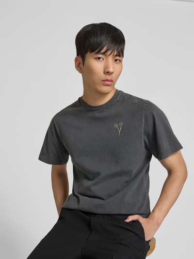 Männermodel trägt T-Shirt mit floralem Stitching von Forét in Dunkelgrau, Reine Baumwolle, Regular-Fit, Rundhalsausschnitt, Kurzärmelig, Ganzkörperansicht von vorne.
