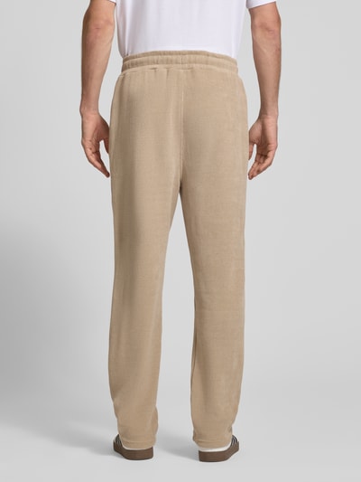 Männermodel trägt Wide Fit Sweatpants mit Label-Detail Modell 'Mezzano' von PEGADOR in Beige, elastischer Material-Mix, Rückansicht, Ganzkörperansicht von hinten.