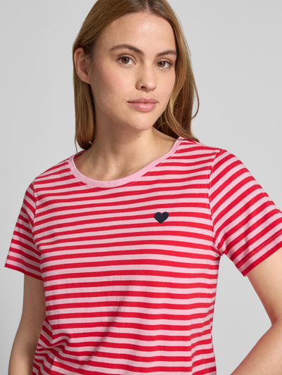Frauenmodel trägt T-Shirt mit Motiv-Stitching und Rundhalsausschnitt von FREE/QUENT, rote und rosa Streifen, reine Baumwolle, Nahaufnahme Oberkörper.