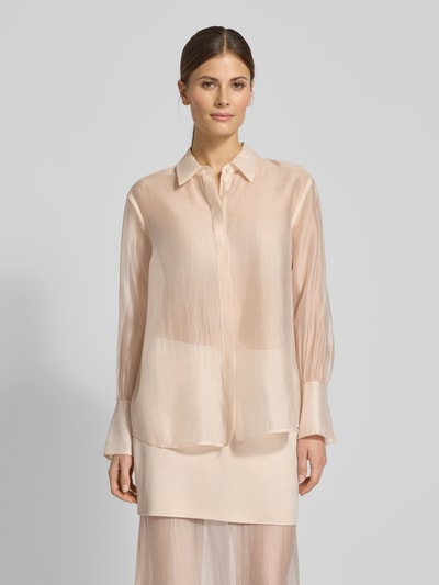 Kobiece modelka nosi Organza-Bluse mit großen Manschetten - curated by Vicky Heiler od SIC, półprzezroczysta, krój regular fit, kołnierzyk koszulowy, długie rękawy, szerokie mankiety, długość tyłu 66 cm, długość rękawa 58 cm, beżowy kolor, tekstura lekko błyszcząca, widok całej sylwetki z przodu.